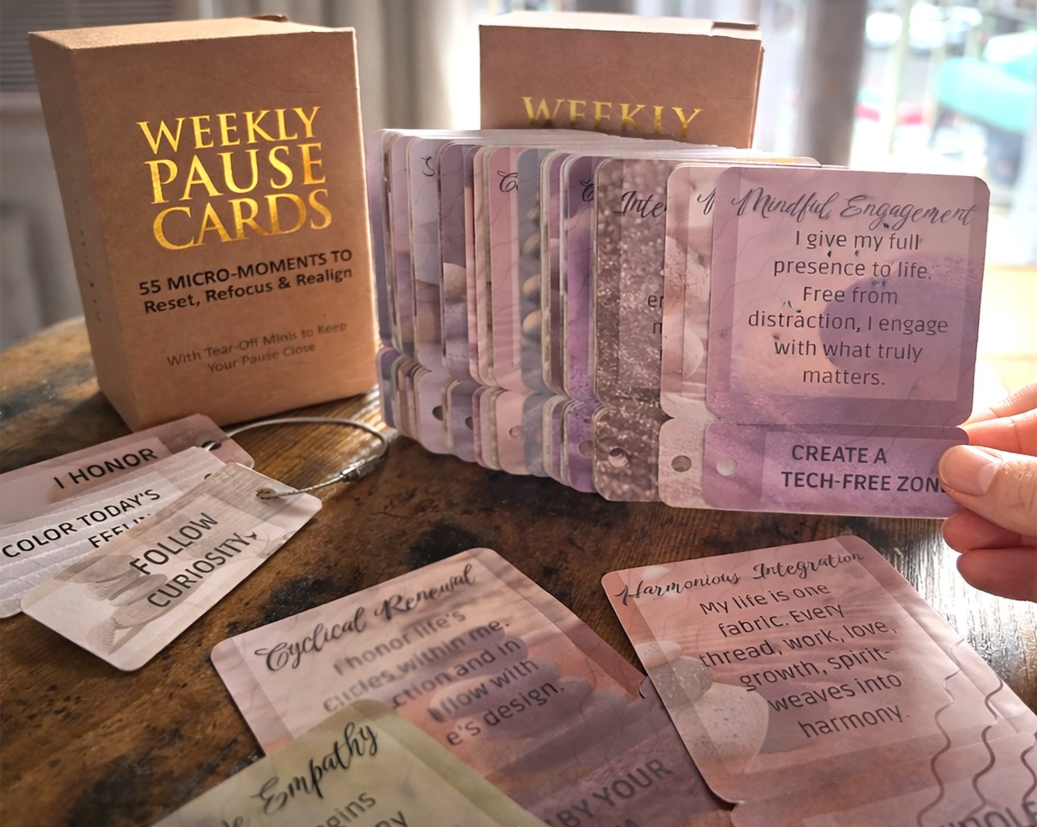 Weekly Pause Cards affirmation cards fanned out on a wooden table by a window